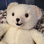 Close-up portrait of an original 1986 Lever Brothers Snuggle Bear featuring expressive brown safety eyes, soft ivory plush, and a classic smiling expression. Perfect for collectors of vintage advertising mascots, retro plush toys, and cozy nursery or shelf decor.