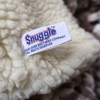 Close-up photograph of the original Snuggle brand tag attached to the vintage 1986 hand puppet, identifying Lever Brothers Company. Original manufacturer tags add authenticity and collector appeal for vintage advertising enthusiasts.