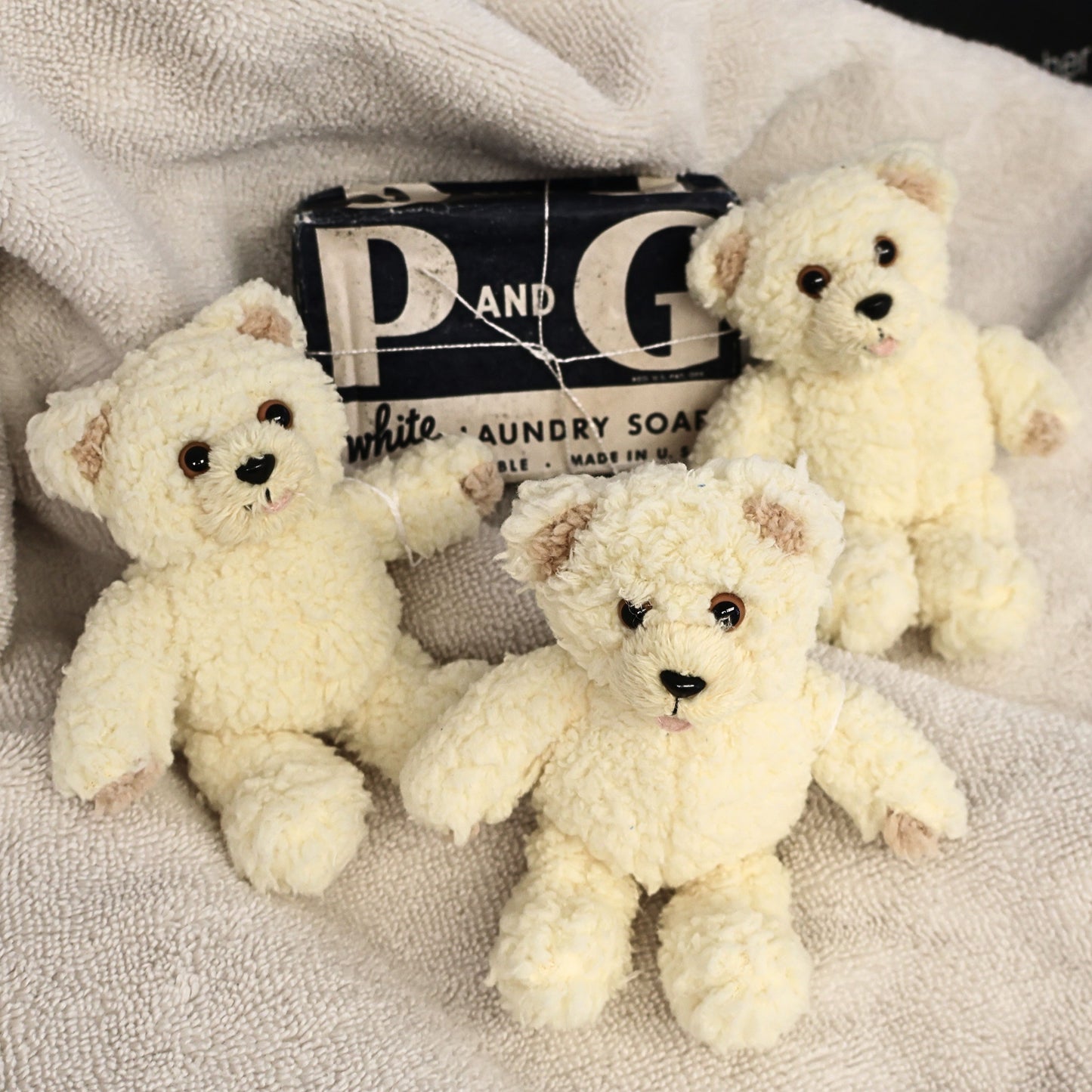 Three vintage Snuggle by GUND mini plush bears displayed beside a classic P&G White Laundry Soap package. This nostalgic advertising collectible features soft ivory plush, sweet embroidered faces, and original tags, making it perfect for retro laundry room decor or vintage mascot collections.