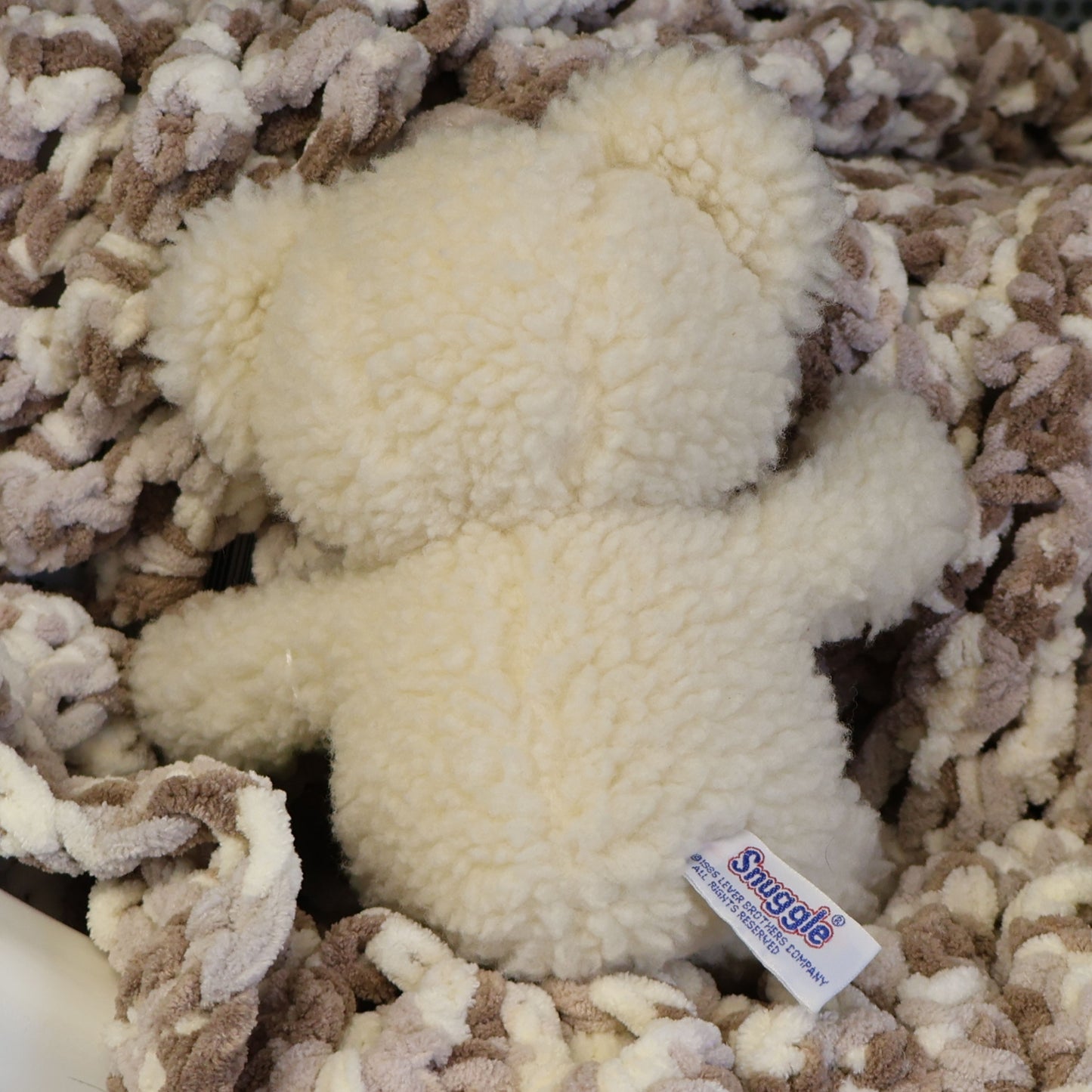 Rear view of a vintage Snuggle plush displaying its original sewn-in Lever Brothers copyright tag and fluffy cream plush. This authentic 1986 advertising mascot is a wonderful addition to nostalgic collections, laundry room decor, or vintage displays.