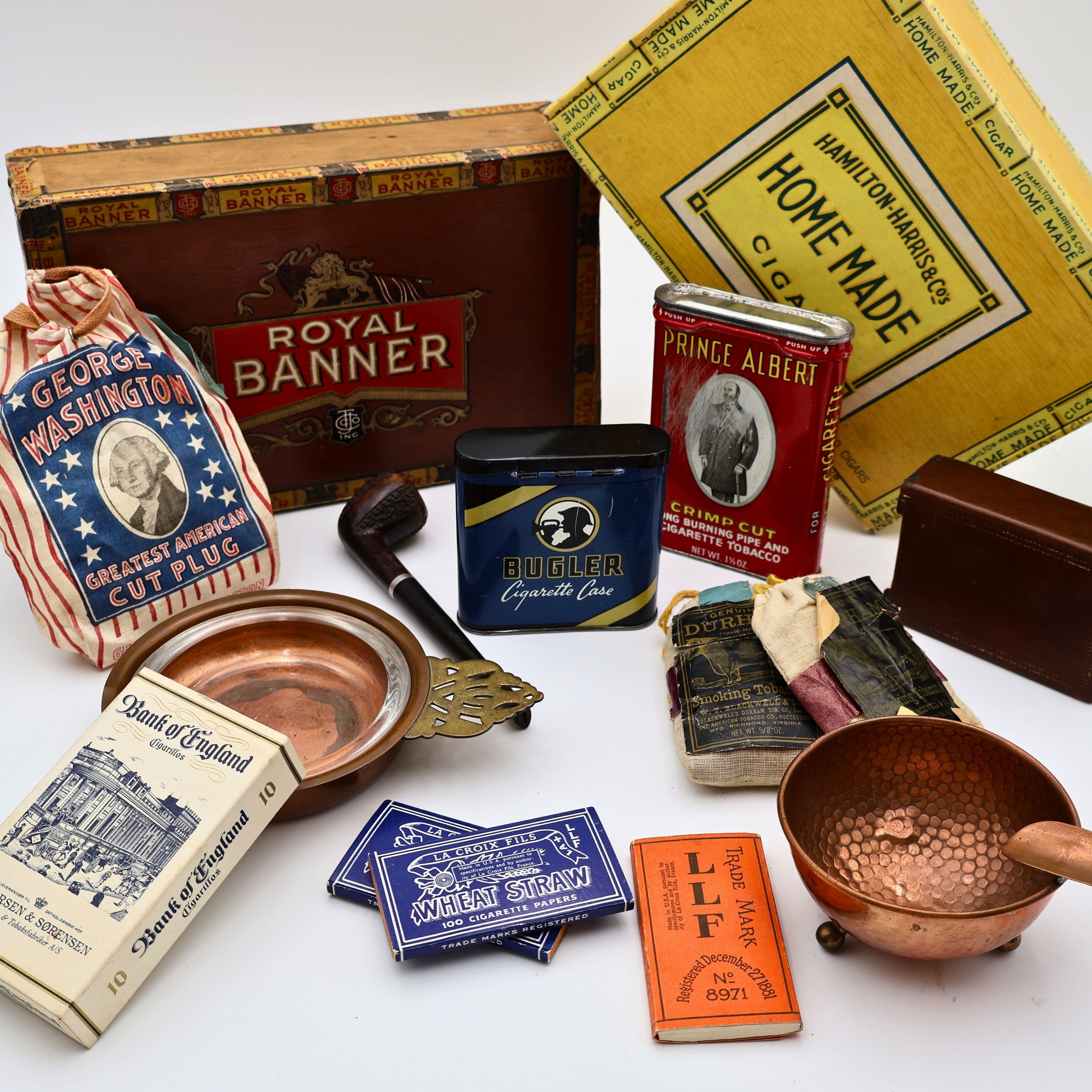 vintage tobacco collection with cigar boxes, smoking tins, pipe, ashtray and rolling papers styled together retro smoke room accessories display