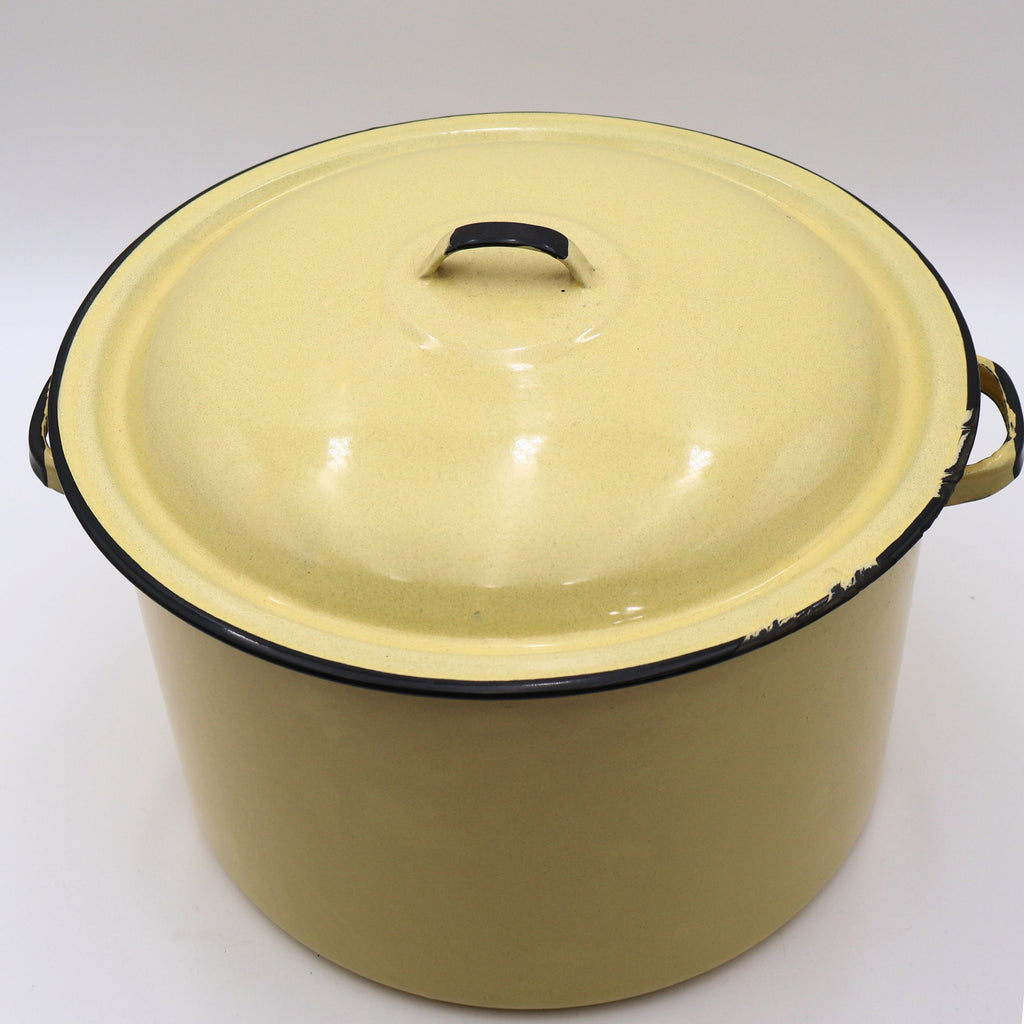 Angled front view of a vintage yellow enamelware stock pot with matching lid showcasing its classic farmhouse silhouette, black trim, and warm buttery yellow finish. A timeless piece for cottagecore décor, vintage kitchen collections, and rustic home styling.
