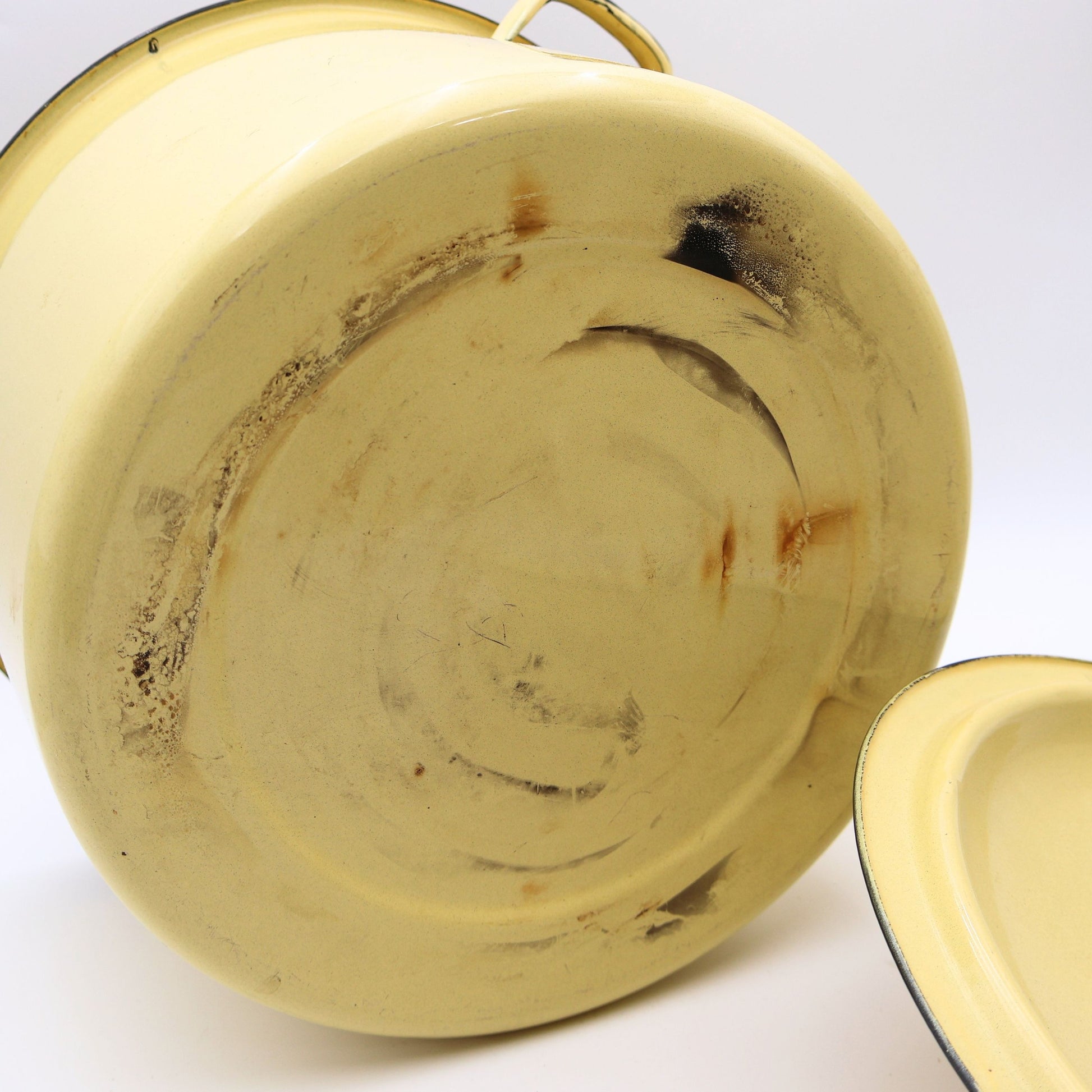 Close-up of the exterior of a vintage yellow enamelware stock pot highlighting authentic enamel wear consistent with decades of careful use. A beautiful example of well-loved vintage farmhouse kitchenware.