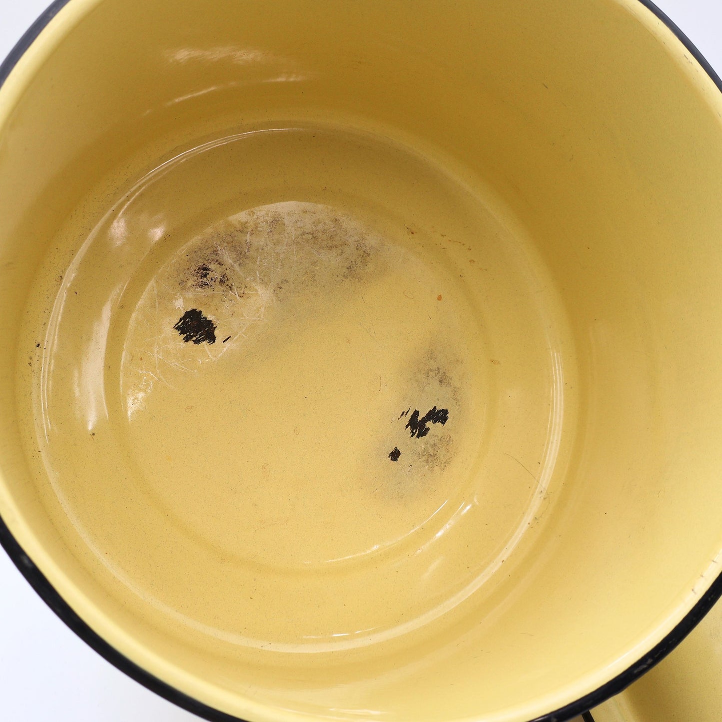 Close-up of the interior of a vintage yellow enamelware stock pot highlighting utensil marks and authentic enamel wear consistent with decades of careful use. A beautiful example of well-loved vintage farmhouse kitchenware.