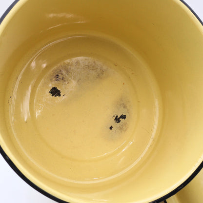 Close-up of the interior of a vintage yellow enamelware stock pot highlighting utensil marks and authentic enamel wear consistent with decades of careful use. A beautiful example of well-loved vintage farmhouse kitchenware.