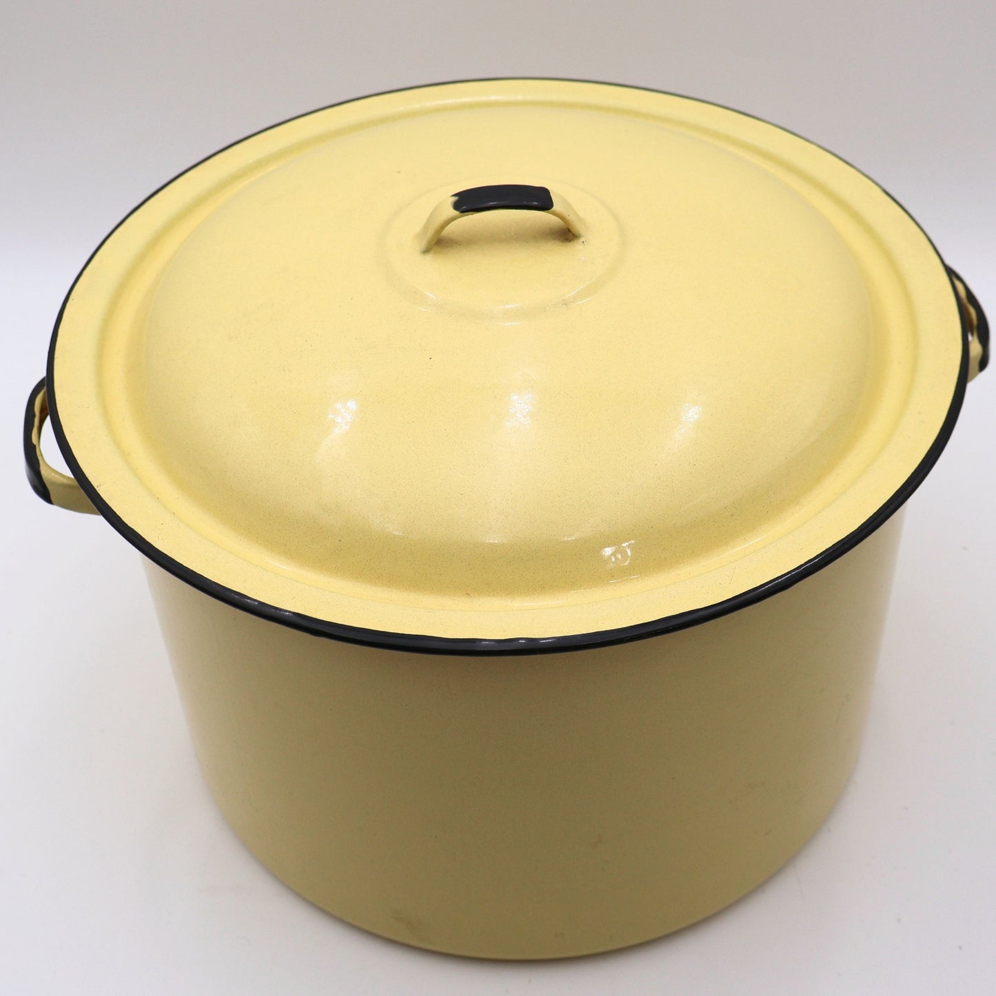 Top view of a vintage yellow enamelware stock pot with matching lid showcasing its classic domed lid, buttery yellow finish, and black trim. A timeless piece of farmhouse kitchen decor with authentic vintage character.