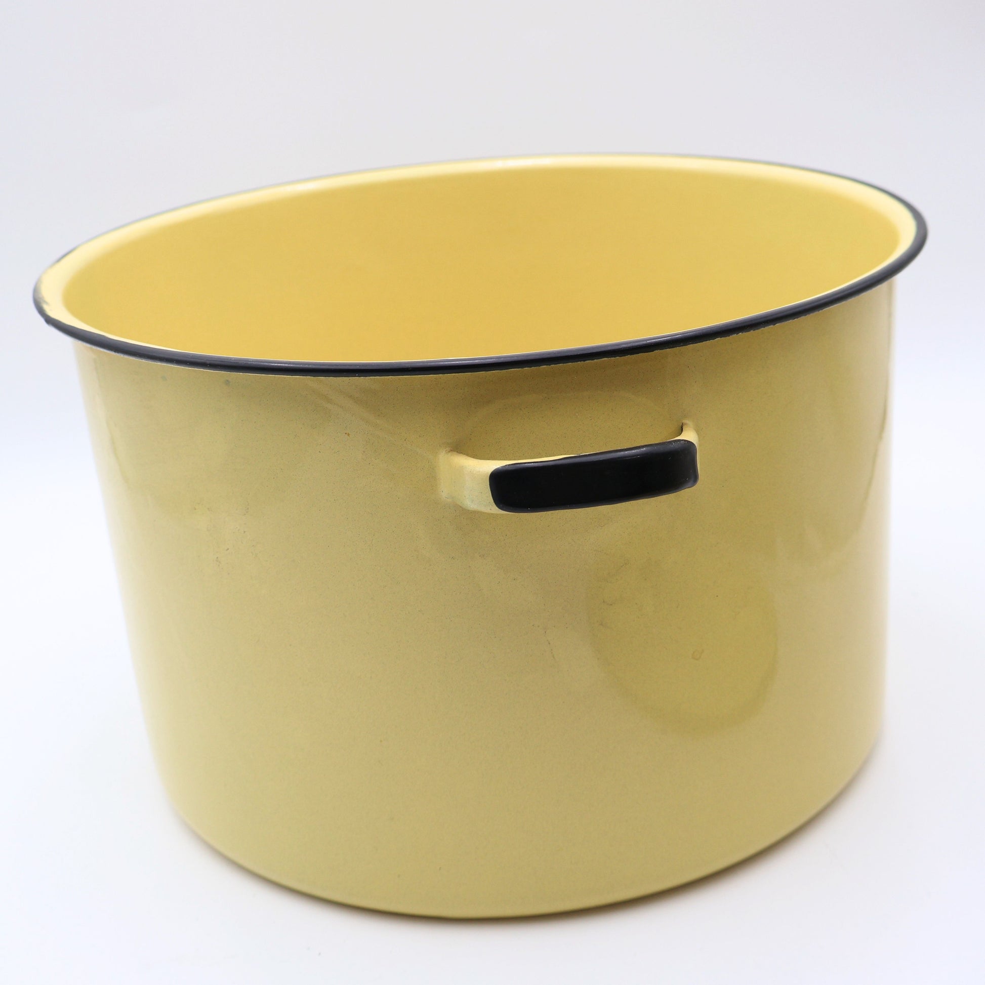 Side profile of a vintage yellow enamelware stock pot featuring classic loop handles, buttery yellow porcelain enamel, and timeless farmhouse styling. This one-of-a-kind vintage cookware piece adds warmth and nostalgia to any kitchen.