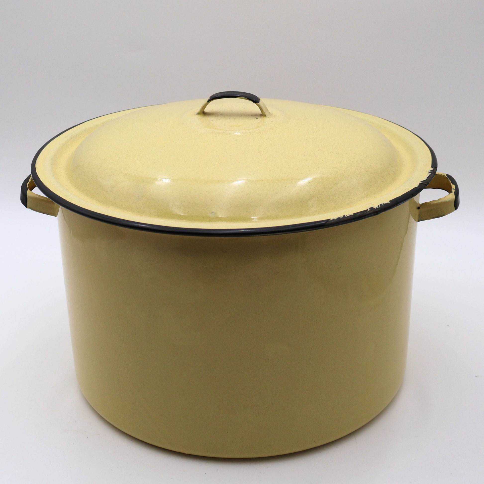 Vintage yellow enamelware stock pot with matching lid featuring a soft buttery yellow finish, black rolled trim, and sturdy side handles. This large farmhouse kitchen pot is perfect for cottagecore decorating, rustic home decor, vintage cookware collections, and timeless kitchen styling.