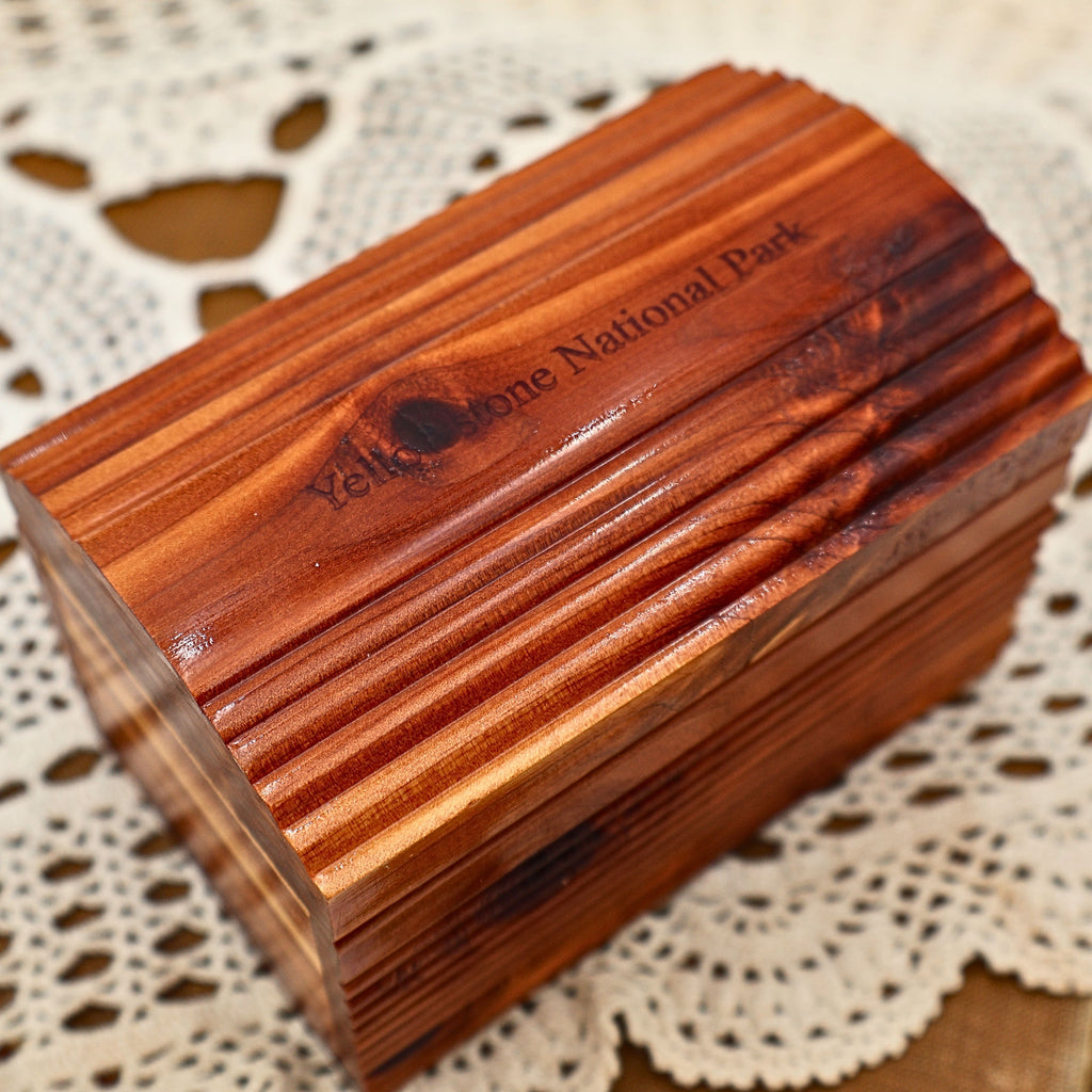 Close-up view of the vintage Yellowstone National Park cedar keepsake box showing the engraved park name across the arched lid. Rich natural cedar grain, distinctive knots, and decorative ribbed carving highlight the craftsmanship of this classic wooden souvenir chest.