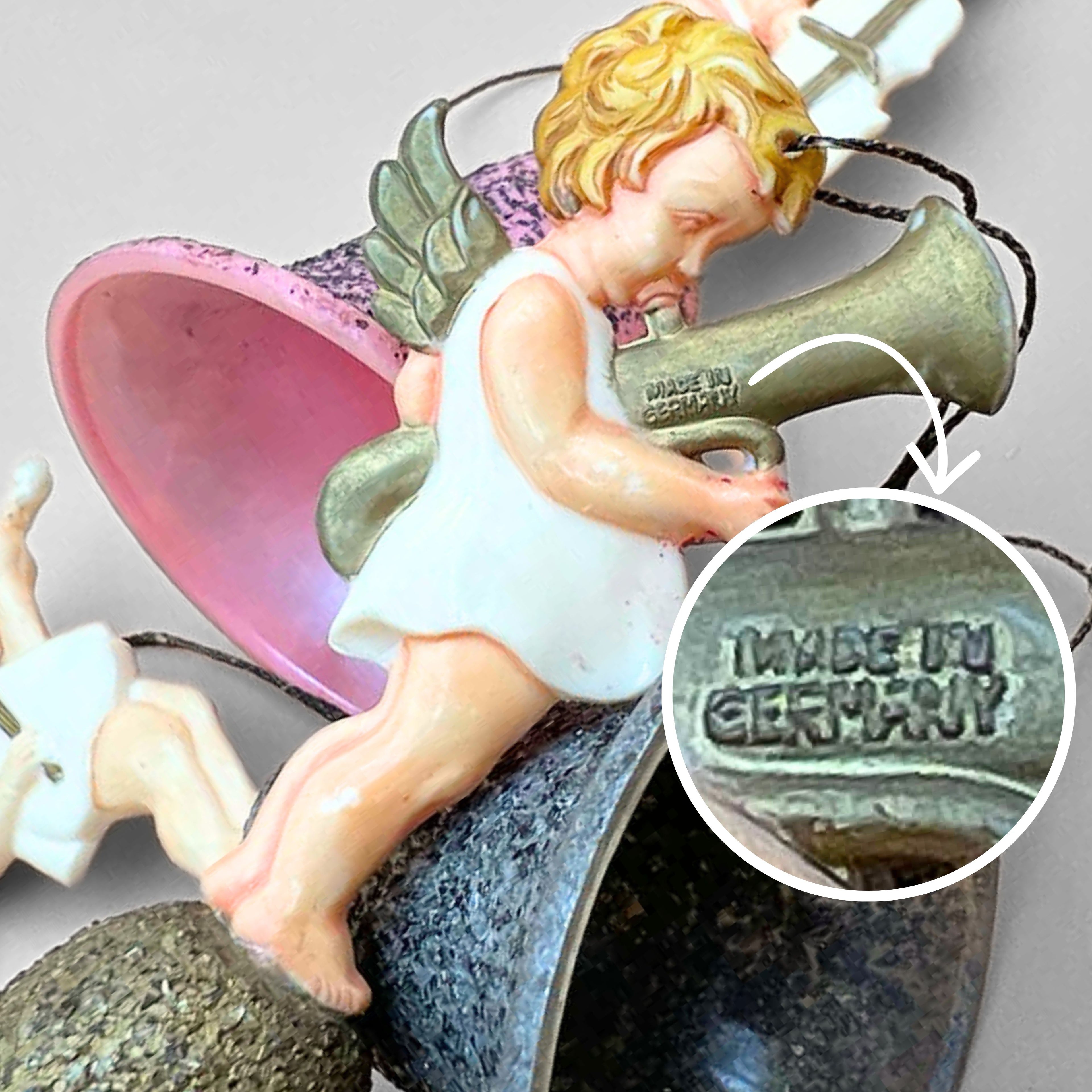 Close-up of vintage angel bell ornament showing embossed West Germany maker marking on horn instrument. Confirms mid century origin and authenticity of German Christmas decor collectible cherub ornament set