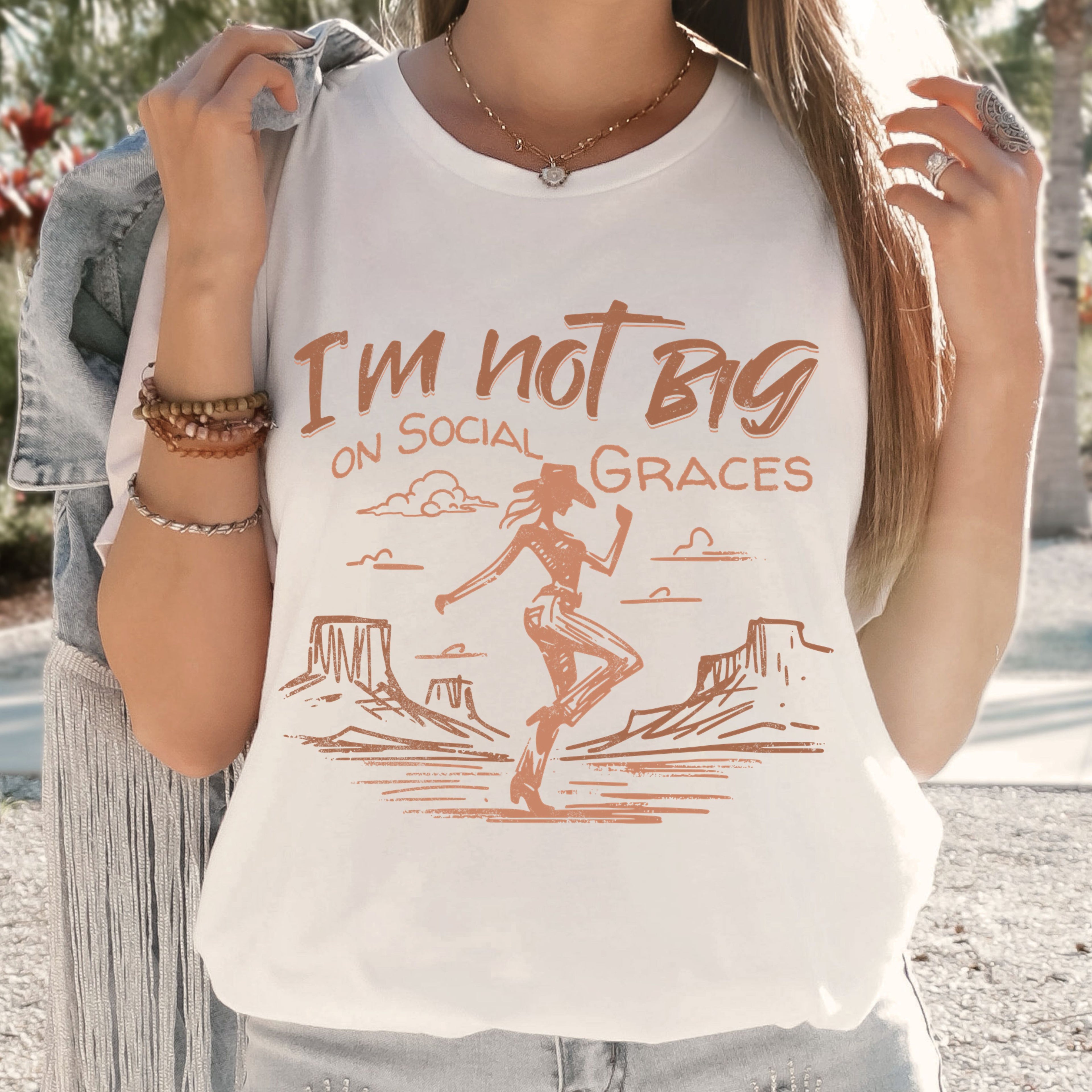 Woman wearing white western graphic tee with cowgirl design and relaxed fit, casual boutique outfit with vintage western style and neutral tones