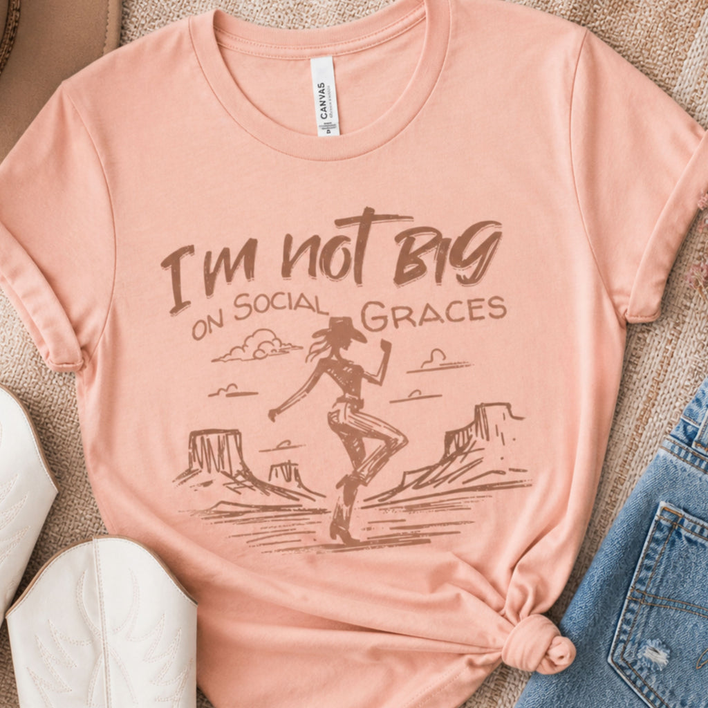 Peach western graphic tee styled with white cowboy boots and denim shorts in a flat lay outfit, boutique cowgirl shirt for casual country inspired looks