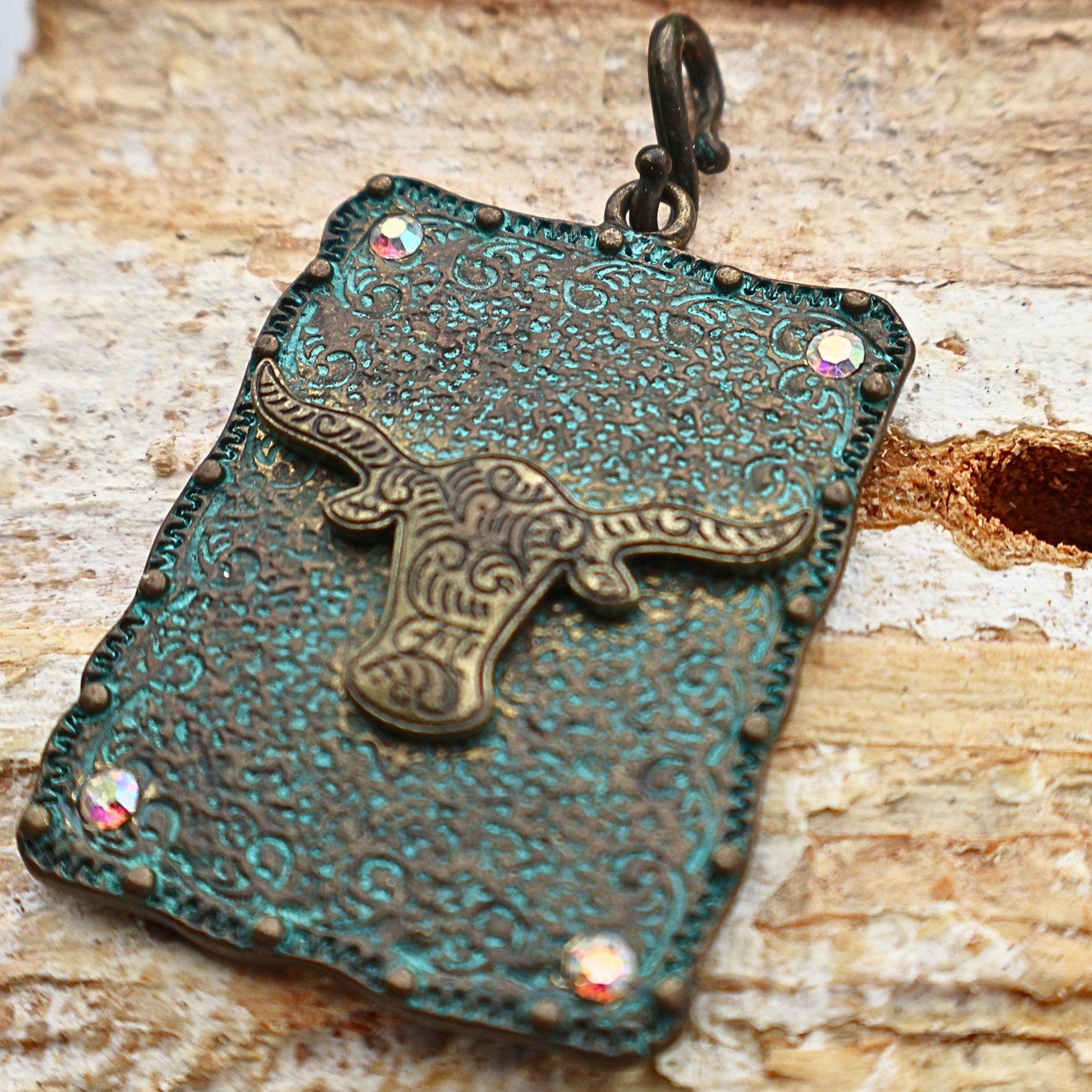 Close-up of Western longhorn pendant with detailed turquoise patina finish and engraved concho design, featuring rhinestone corner accents and rustic textured metal, Southwestern cowgirl necklace charm with bold Western aesthetic, perfect for layering or standalone statement jewelry, ideal for rodeo style, country outfits, and rustic fashion looks