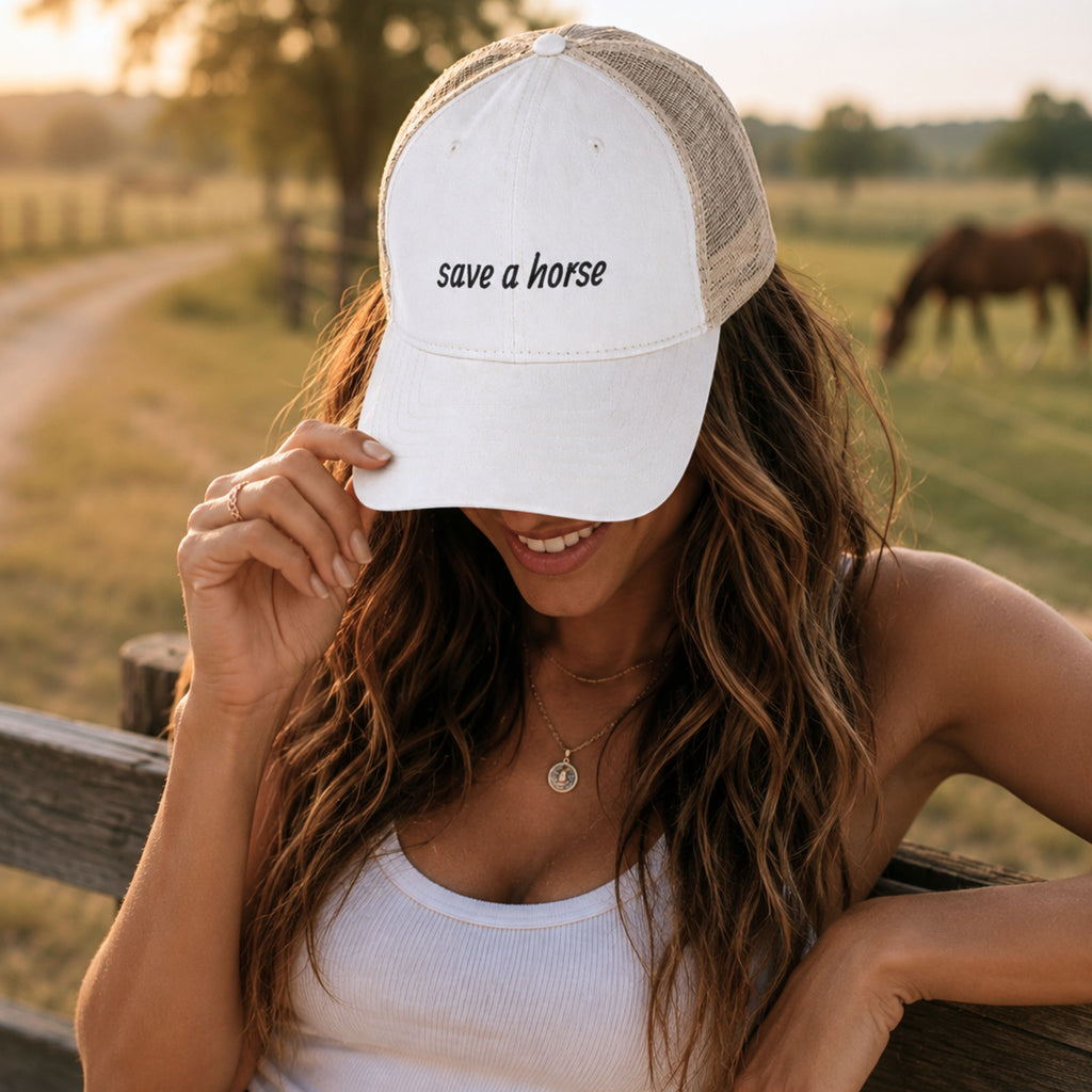 Woman wearing cream western trucker hat with save a horse embroidery outdoors in a country-inspired western setting
