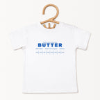 White butter foodie kids shirt displayed on hanger with retro bakery inspired graphic design. Boutique toddler birthday apparel styled for preschool outfits, baking themes, family photos, and playful celebrations.