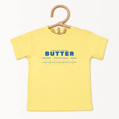 Yellow butter toddler tee displayed on wooden hanger featuring retro sweet cream baking graphic and foodie inspired design. Boutique kids birthday shirt perfect for preschool outfits, parties, and playful everyday wear.