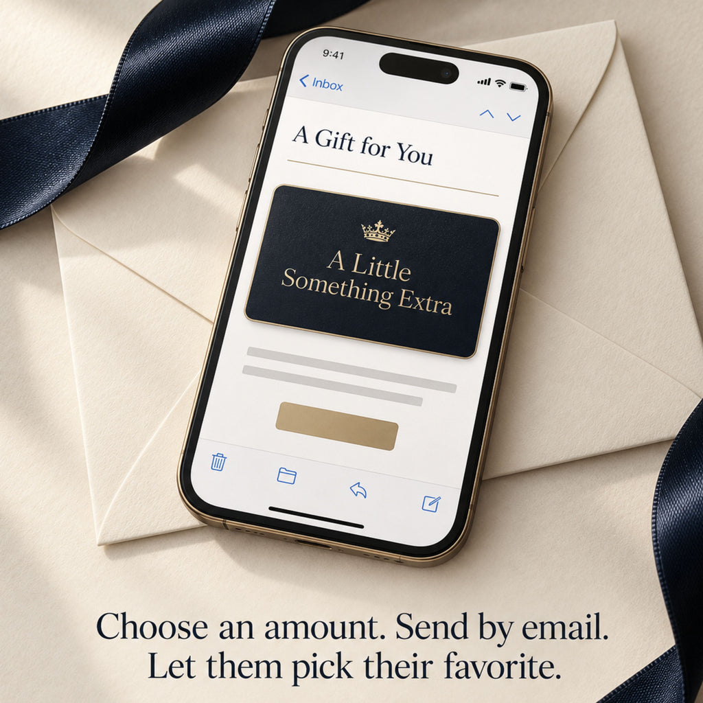 Smartphone displaying an emailed Zestful Productions gift card with a gold crown and the words A Little Something Extra. The phone rests on ivory envelopes beside navy satin ribbon with the message Choose an amount. Send by email. Let them pick their favorite.