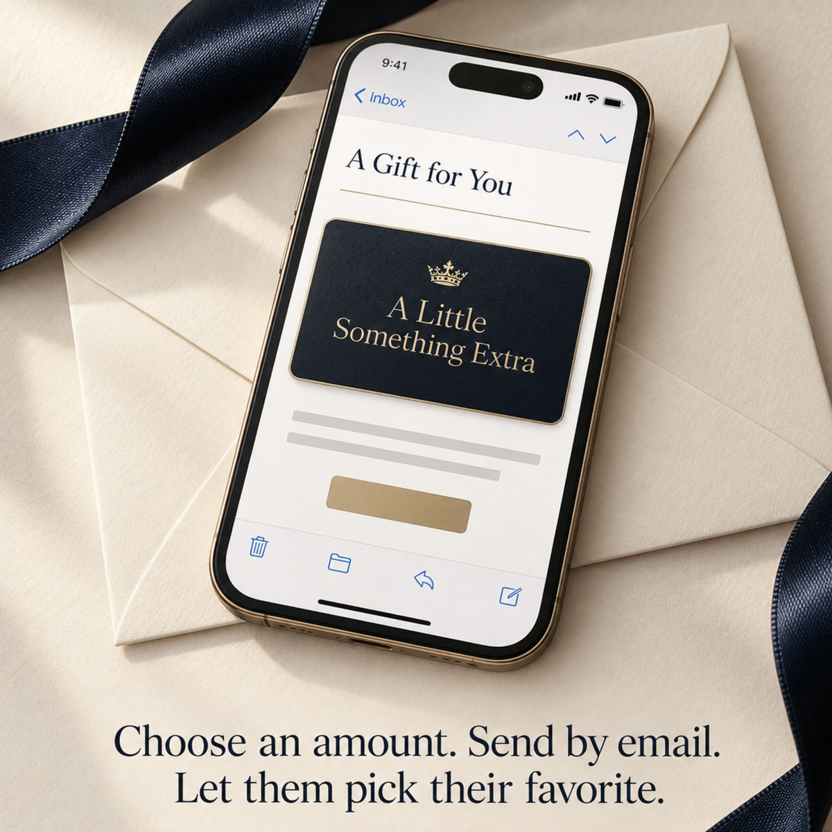 Smartphone displaying an emailed Zestful Productions gift card with a gold crown and the words A Little Something Extra. The phone rests on ivory envelopes beside navy satin ribbon with the message Choose an amount. Send by email. Let them pick their favorite.