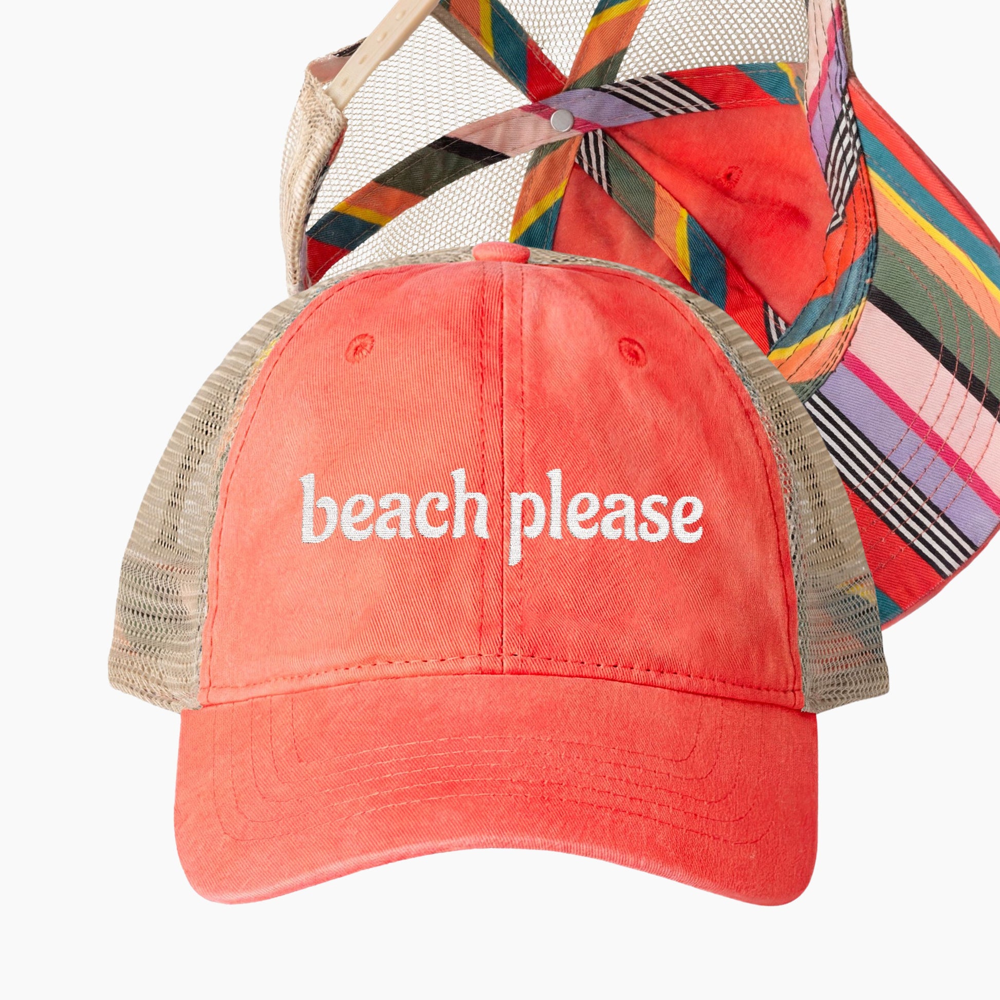 Beach please embroidered coral trucker hat with colorful striped underbrim shown in flat lay product image