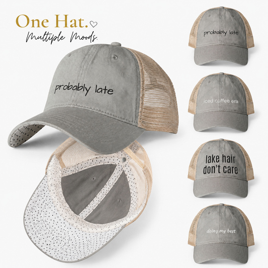 Gray and beige women’s mesh-back trucker hat collection featuring interchangeable embroidered phrases including “probably late,” “iced coffee era,” “lake hair don’t care,” and “doing my best” with polka dot underbrim detail and “One Hat Multiple Moods” text on a clean white background