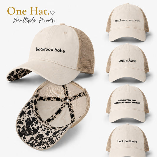 Cream western mesh-back ponytail trucker hat with cow print longhorn undervisor shown in multiple embroidered phrase variations including backroad babe and save a horse