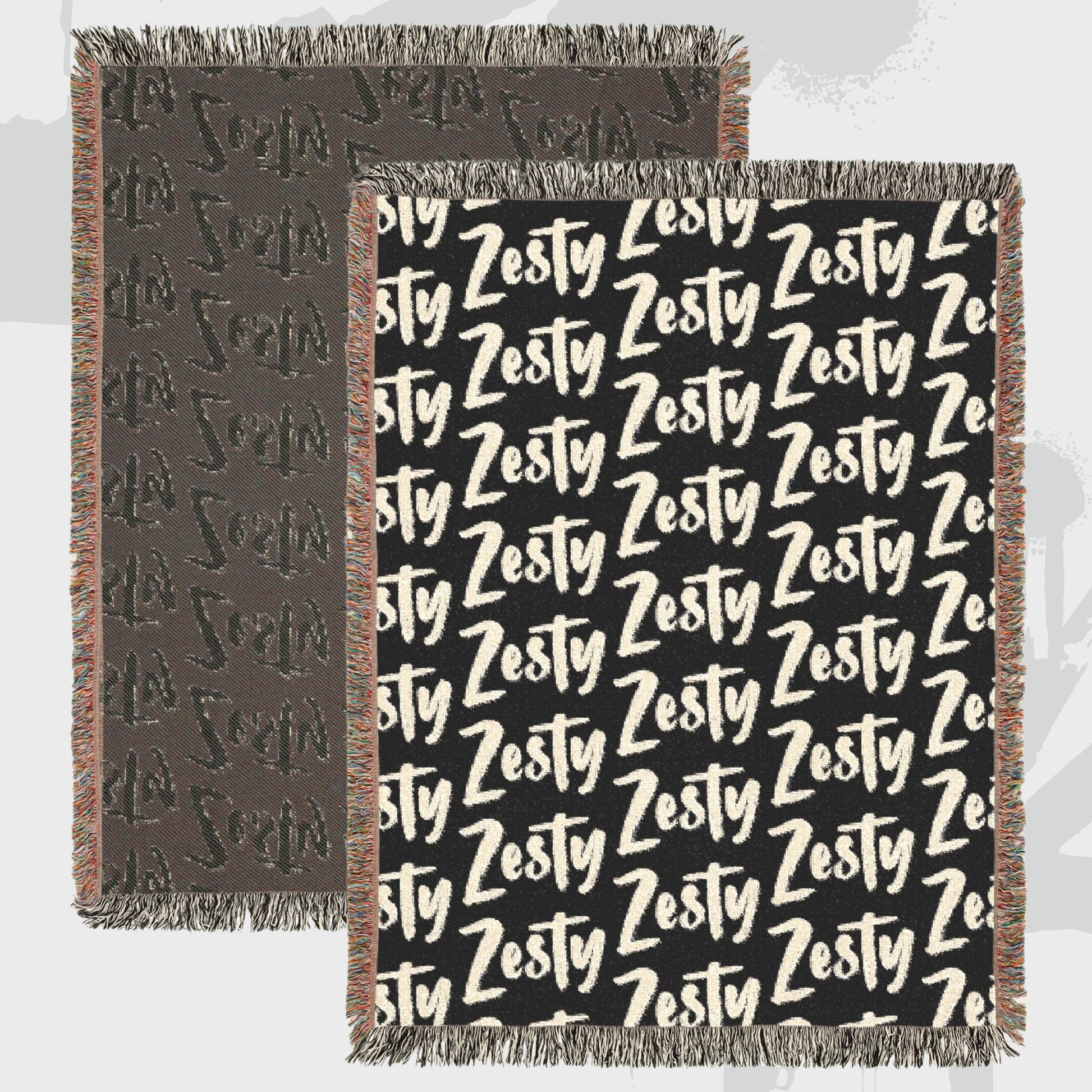 Close-up of woven cotton throw blanket showing bold Zesty text pattern