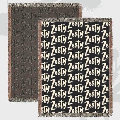 Close-up of woven cotton throw blanket showing bold Zesty text pattern
